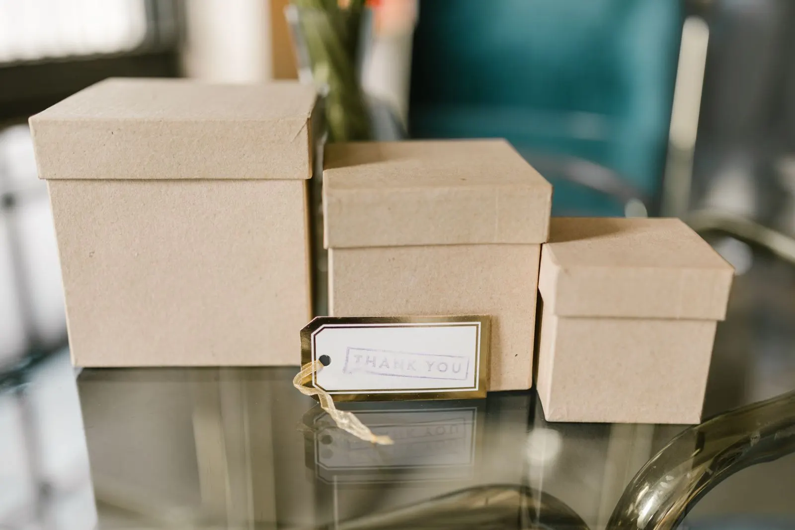 Three kraft boxes with lids in different sizes, with a thank-you tag tied to the front